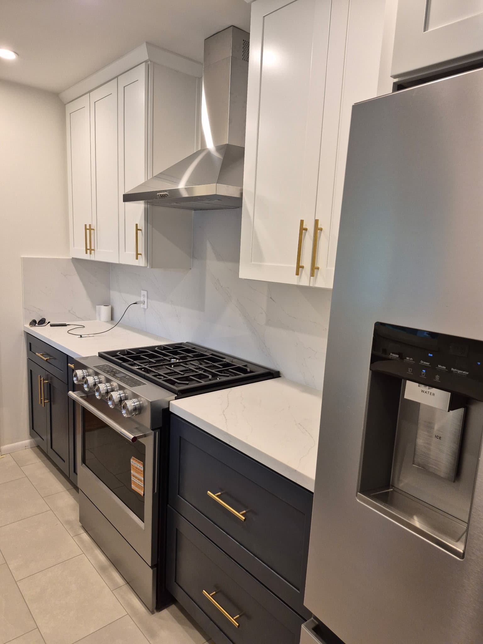 Renovated kitchen featuring a stainless gas range, marble-look backsplash, and two-tone cabinetry.